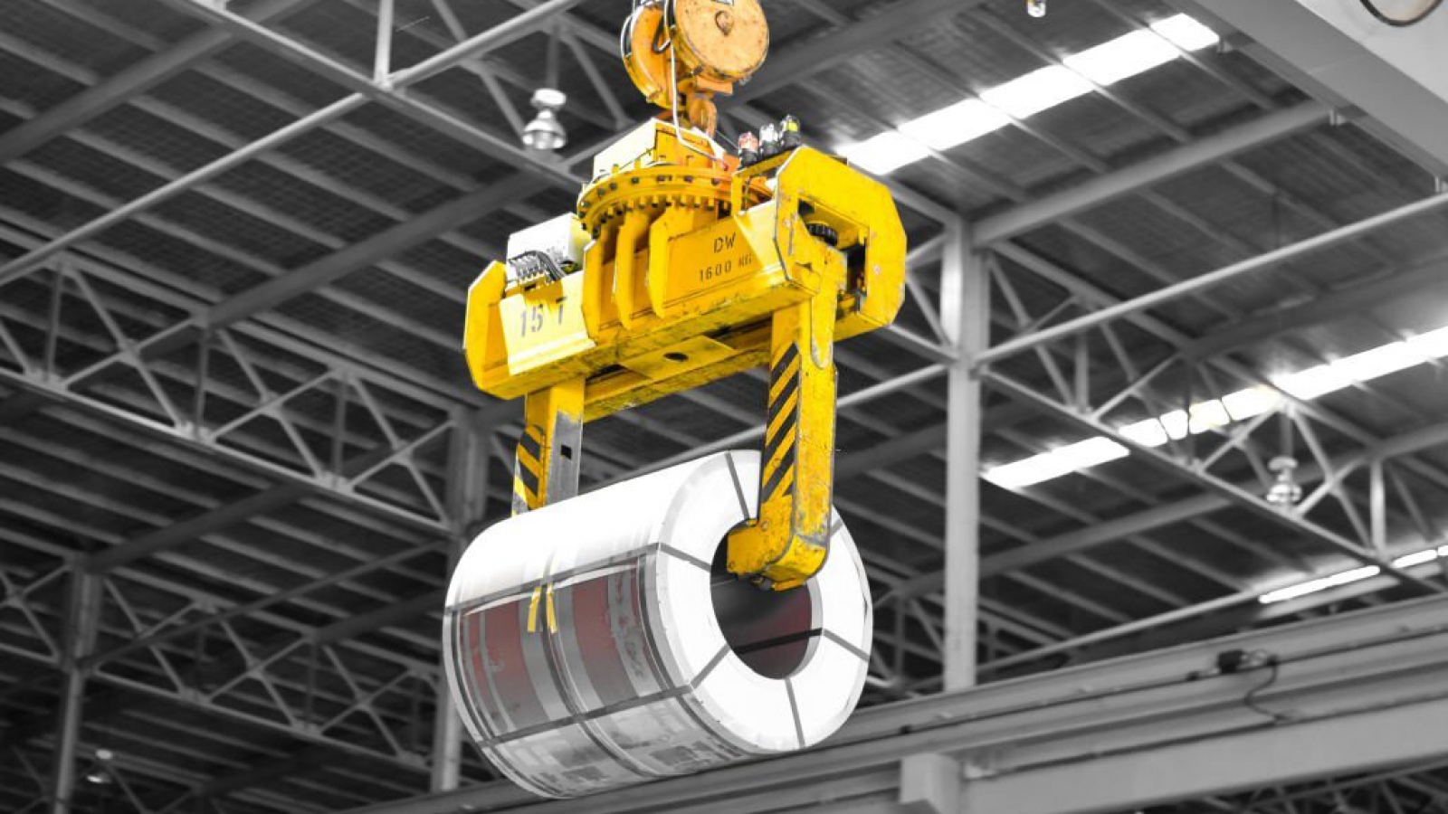 Overhead crane lift up steel coil with tong in warehouse. Steel coils handling equipment. Steel warehouse and logistics operations.