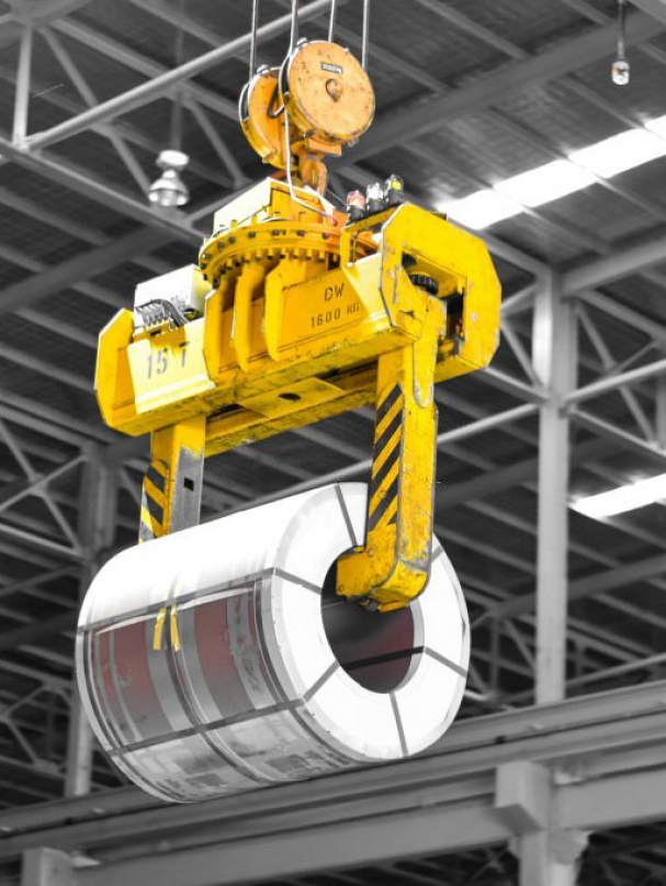 Overhead crane lift up steel coil with tong in warehouse. Steel coils handling equipment. Steel warehouse and logistics operations.
